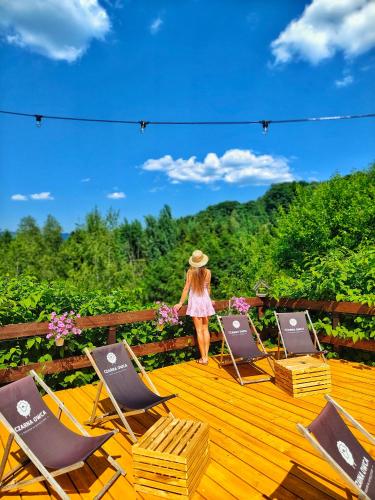 a woman standing on a deck with four lawn chairs at Czarna Owca in Istebna
