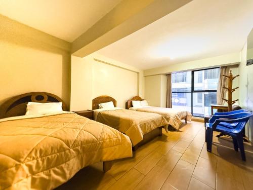 a hotel room with two beds and a blue chair at Hotel Qoyllur urcos in Urcos