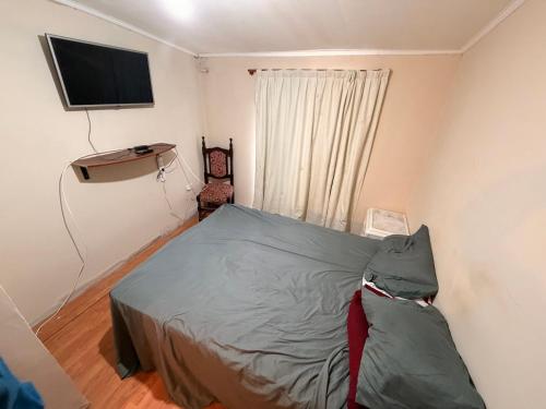 a small bedroom with a bed and a flat screen tv at Deptos Valen in Trevelín
