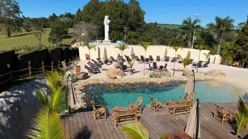 a pool with chairs and umbrellas and a fountain at Cabana's Acqua Hotel in Águas de Lindoia