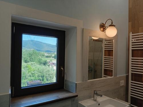 a bathroom with a window with a sink and a mirror at I leoni di Montecchio in Castiglion Fiorentino
