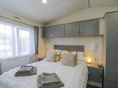 a bedroom with a bed with pillows and a window at The Cotswold Holiday Lodge in Evesham