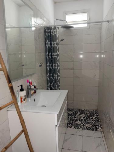 a white bathroom with a sink and a shower at Logement au vauclin in Le Vauclin