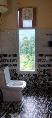 a bathroom with a toilet and a window at Your Slow House in Shangarh