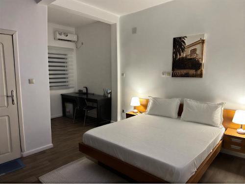 a bedroom with a white bed and a desk at Melroseplace Complex in Bonabéri