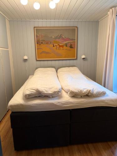 a bed in a bedroom with a painting on the wall at Dalhus Valley Apartment in Norddal