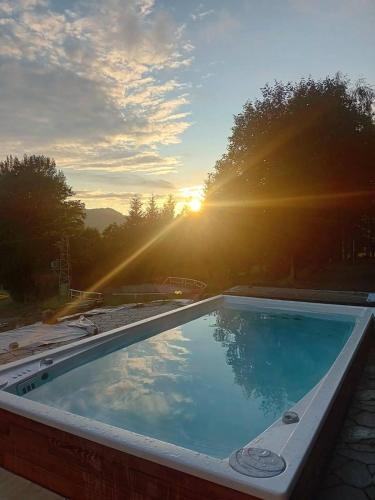 a swimming pool with the sunset in the background at Chalupa Šťastný kopec in Deštné v Orlických horách