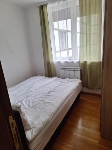 a small bedroom with a bed and a window at Apartman Glorija in Brzeće