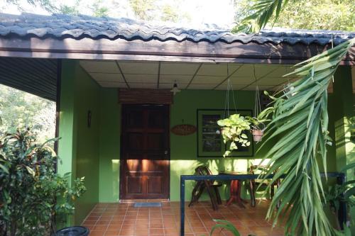 a green house with a wooden door and a table at Kwainoy Riverpark in Sai Yok