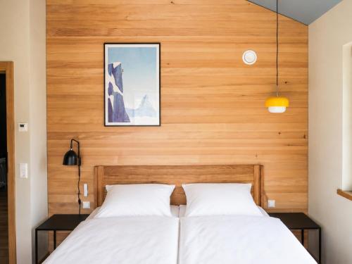 two beds in a bedroom with a wooden wall at Das Kofelau in Oberammergau