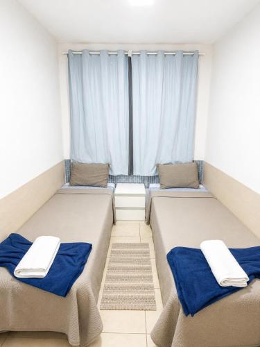 two beds in a small room with a window at Apt da Leily in São Luís