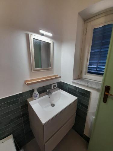 ein Badezimmer mit Waschbecken, Spiegel und Fenster in der Unterkunft Lumie in Palermo