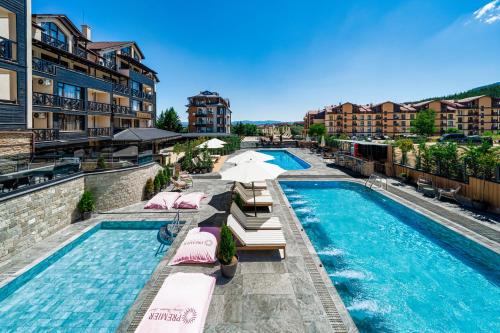 a resort pool with lounge chairs and umbrellas at Premier Luxury Mountain Resort in Bansko