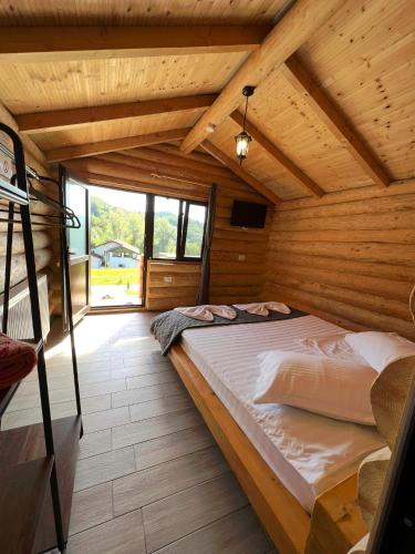 a bedroom with a large bed in a wooden house at Cabanutele M&V INFINIT in Sălătrucel