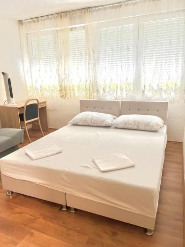 a white bed in a room with a window at Tinela in Mostar