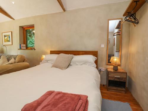 a bedroom with a large white bed and a couch at Brambly Cabin in Crediton