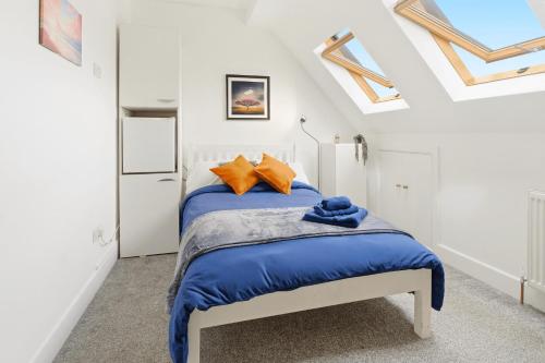 a bedroom with a bed with blue sheets and orange pillows at Sky View En-Suite in Egham