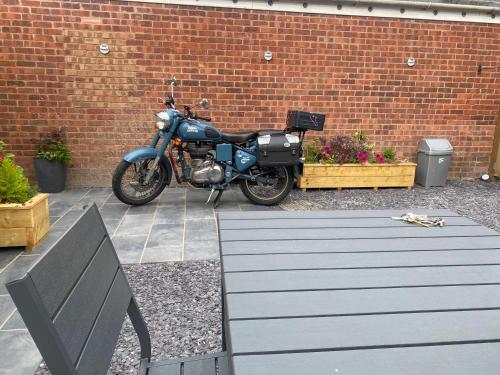 a blue motorcycle parked in front of a brick wall at Holiday home with 3 double bedrooms all En-suite in Craven Arms
