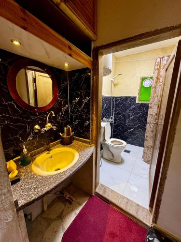 a bathroom with a yellow sink and a toilet at Oak Farm مزرعة الملّول in Ajloun