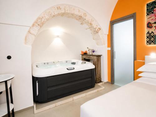 a bathroom with a bath tub next to a bed at Ostuni Luxury Room in Ostuni