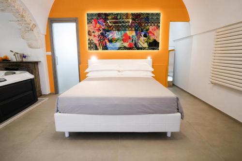 a bedroom with a white bed with an orange wall at Ostuni Luxury Room in Ostuni