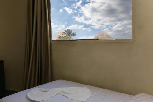a window with a towel on a bed with the pyramids at Happy View INN in Giza