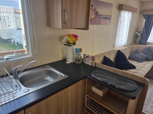 a kitchen with a sink and a couch in a caravan at Beautiful 8 Berth - Caravan - Abergele in Abergele