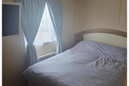 a bedroom with a bed and a window with a white sheet at Beautiful 8 Berth - Caravan - Abergele in Abergele