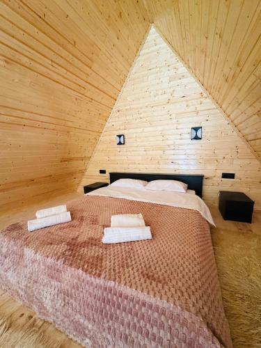 a bed in a wooden room with two towels on it at River Sound Chalet in Tba