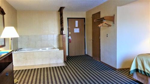 a hotel room with a bath tub and a bed at Super 8 by Wyndham Iowa Falls in Iowa Falls