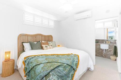 a white bedroom with a large bed and a sink at 'Still & Sea' in Yeppoon's CBD in Yeppoon