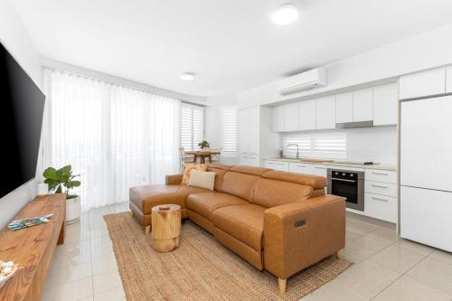 a living room with a brown couch in a kitchen at 'Still & Sea' in Yeppoon's CBD in Yeppoon