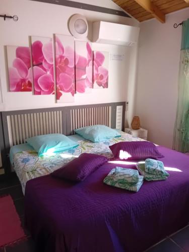 a bedroom with a purple bed with towels on it at Gîte Anolis in Saint-François