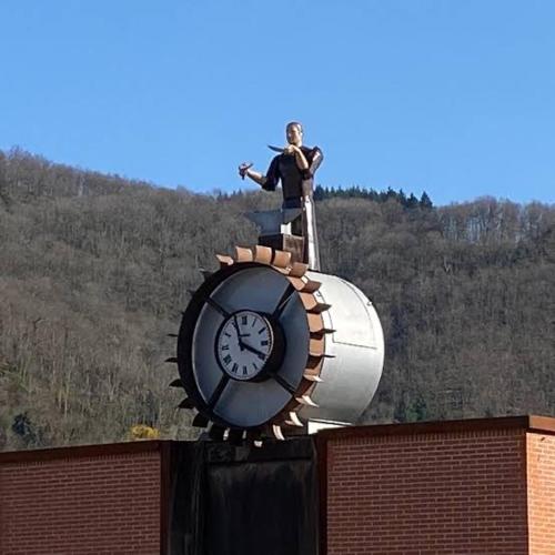 a man standing on top of a clock on top of a building at A côté de la Gare in Thiers