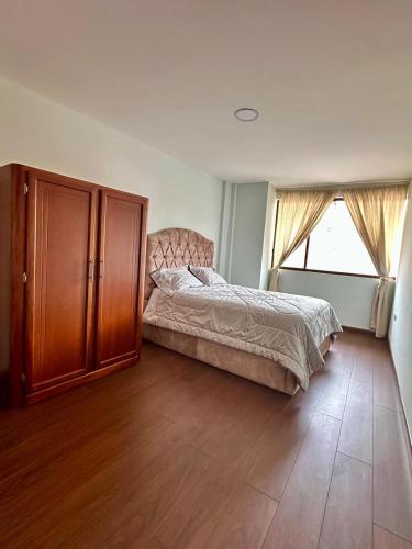 a bedroom with a bed and a cabinet and a window at "Wampu" - Amplio apartamento cerca del Centro Histórico in Cuenca