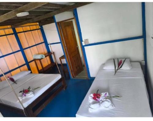 a room with two beds with flowers on them at Cabañas Guaimia in Nuquí