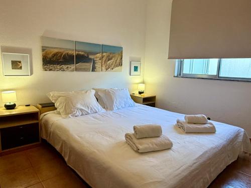 a bedroom with a white bed with two towels on it at Moradia Vila Real Sto Antonio in Vila Real de Santo António