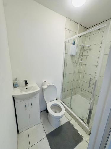 a bathroom with a shower and a toilet and a sink at The Heath Haven- Morden 4 Bedroom House Near Station High Street, Free Parking WiFi in Goodmayes