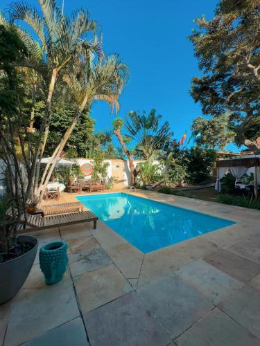 a swimming pool with a bench and palm trees at Casa Valldemossa in Búzios