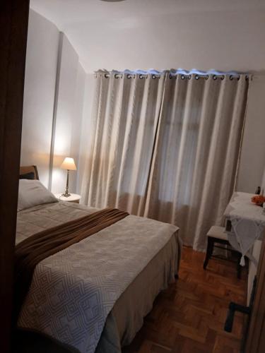 a bedroom with a bed and a window with curtains at Ita Green in Teresópolis