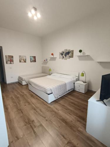 a white bedroom with a large bed and wooden floors at Manì Rooms Villanova in Cagliari
