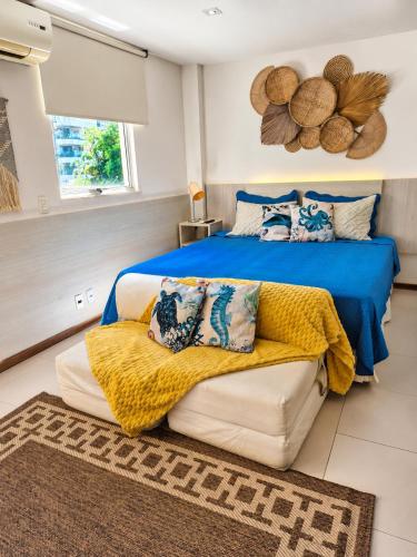 a bedroom with a bed and a couch with a yellow blanket at Apartamento no Hotel Porto Marina Mangaratiba in Mangaratiba
