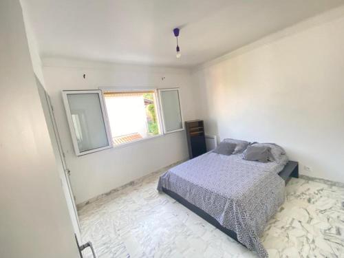 a white bedroom with a bed and a window at Villa Emeraude in Cagnes-sur-Mer