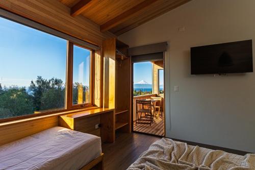 a bedroom with a bed and a tv and a balcony at Ave Lodge Frutillar in Frutillar