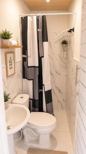 a bathroom with a black and white shower curtain and a toilet at Brisa y Lienzo - Hostal Boutique in Puerto Colombia