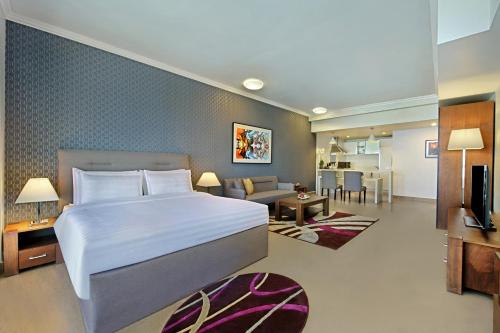 ドーハにあるThe Curve Hotelの大きなベッドとリビングルームのある寝室