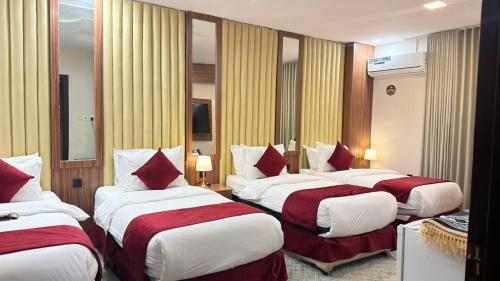 a hotel room with three beds with red and white pillows at الجوهرة بارك للشقق المخدومة 6 in Riyadh