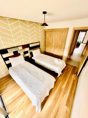 two beds in a room with wood flooring at Appartement Cozy avec piscine in Sidi Rahal