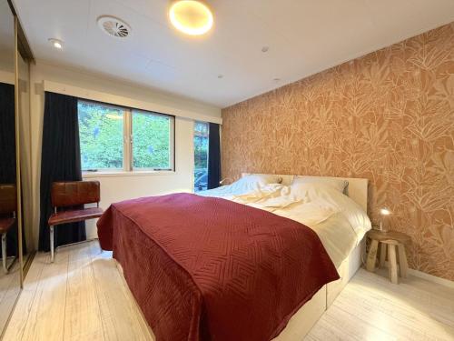 a bedroom with a large bed with a red blanket at Villaatje Veluwe in Garderen