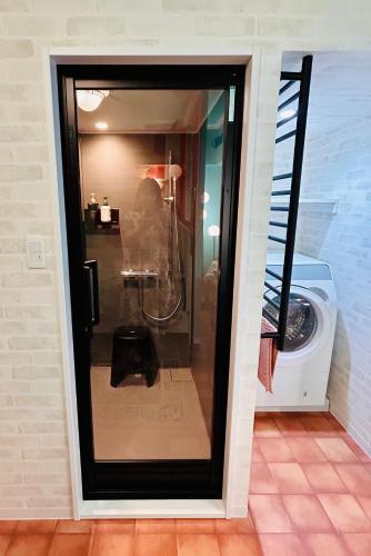 una porta doccia in vetro in un bagno con lavatrice di Flat 106 a Tokyo